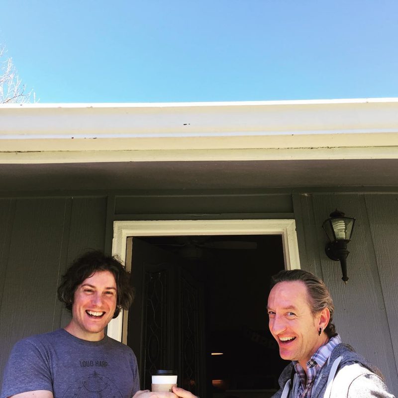 Gary and a friend laughing over coffee on a front porch, 2016